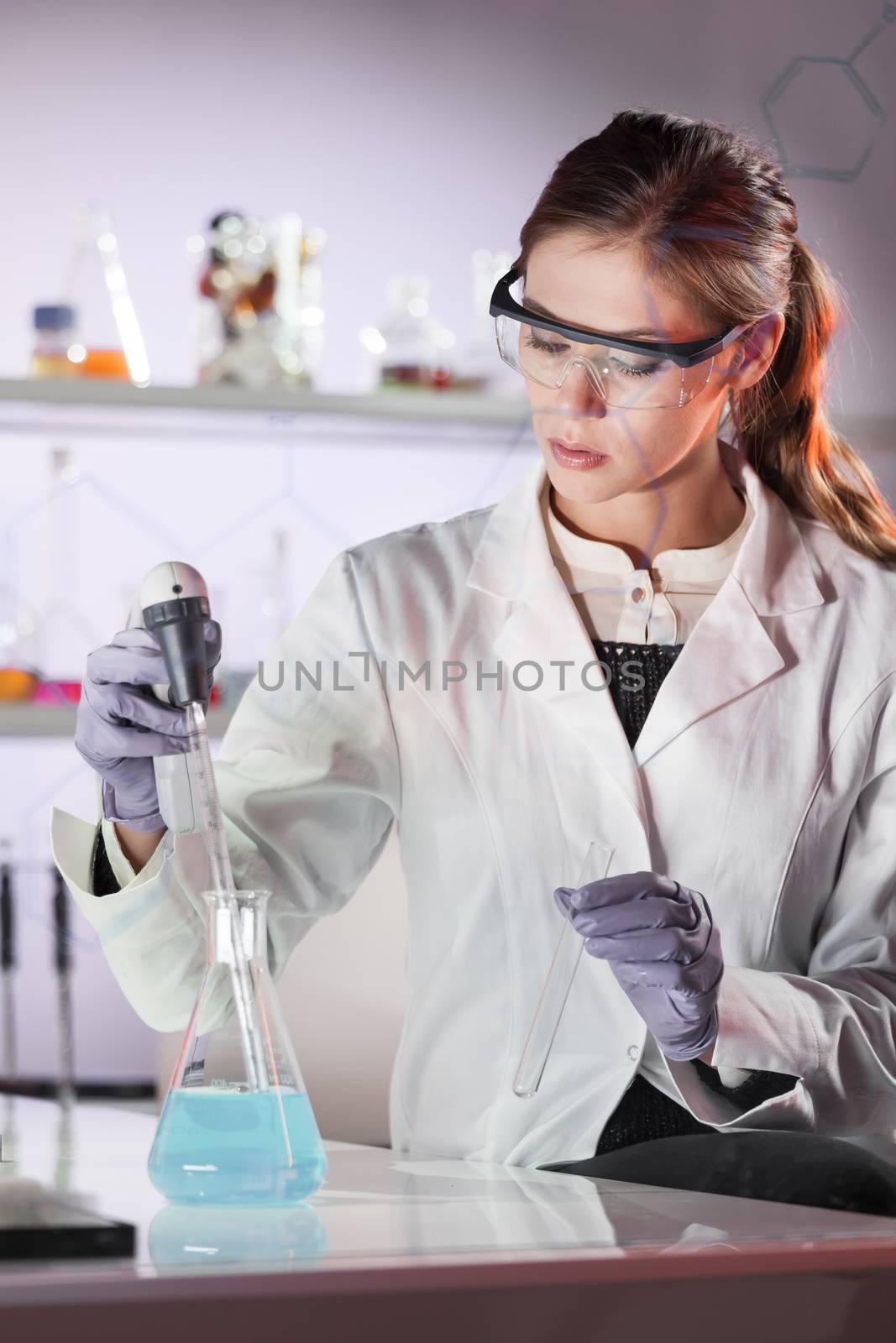 Life scientists researching in laboratory. Focused female life science professional pipetting solution into the glass cuvette. Lens focus on researcher's eyes. Healthcare and biotechnology concept.