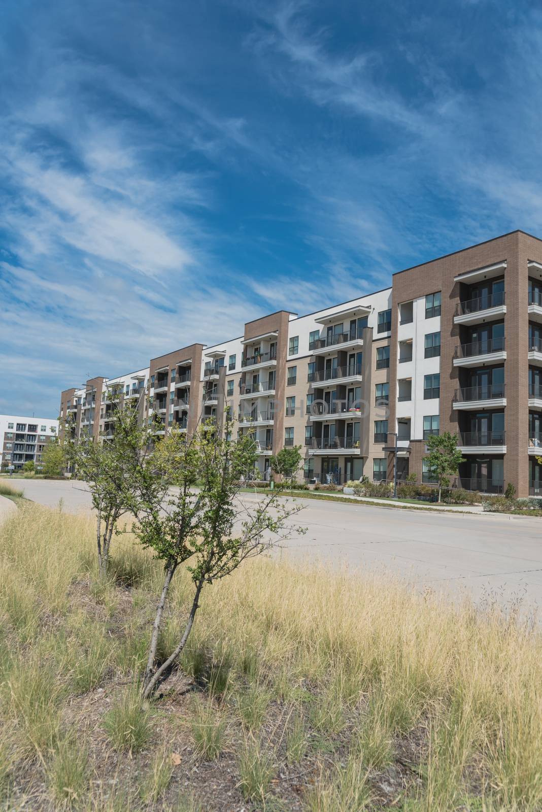 Row of apartment buildings near street in suburbs area of Dallas, Texas, USA. Multi-Storey flat unit, group housing complex condos for modern living style