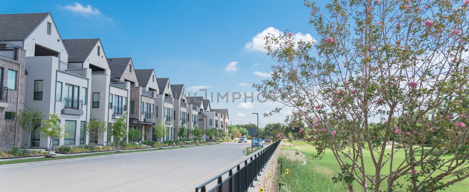 Panorama park side brand new row of three story single family houses in Richardson, North Dallas. Modern design of urban living residences with side private courtyards near large street and fence