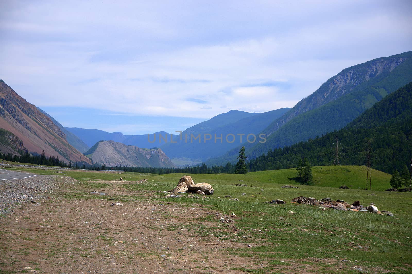 Stone boulders lying on the side of the road passing through a mountain valley. Altai, Siberia, Russia.