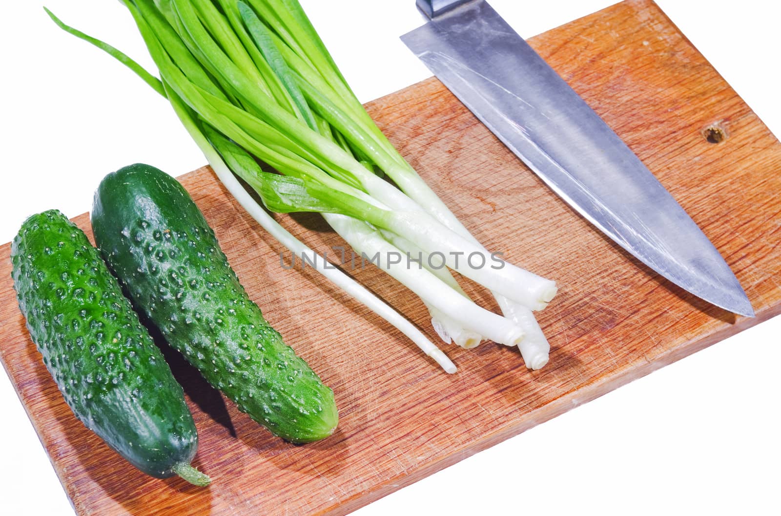 fresh cucumbers and green onions on a cutting board