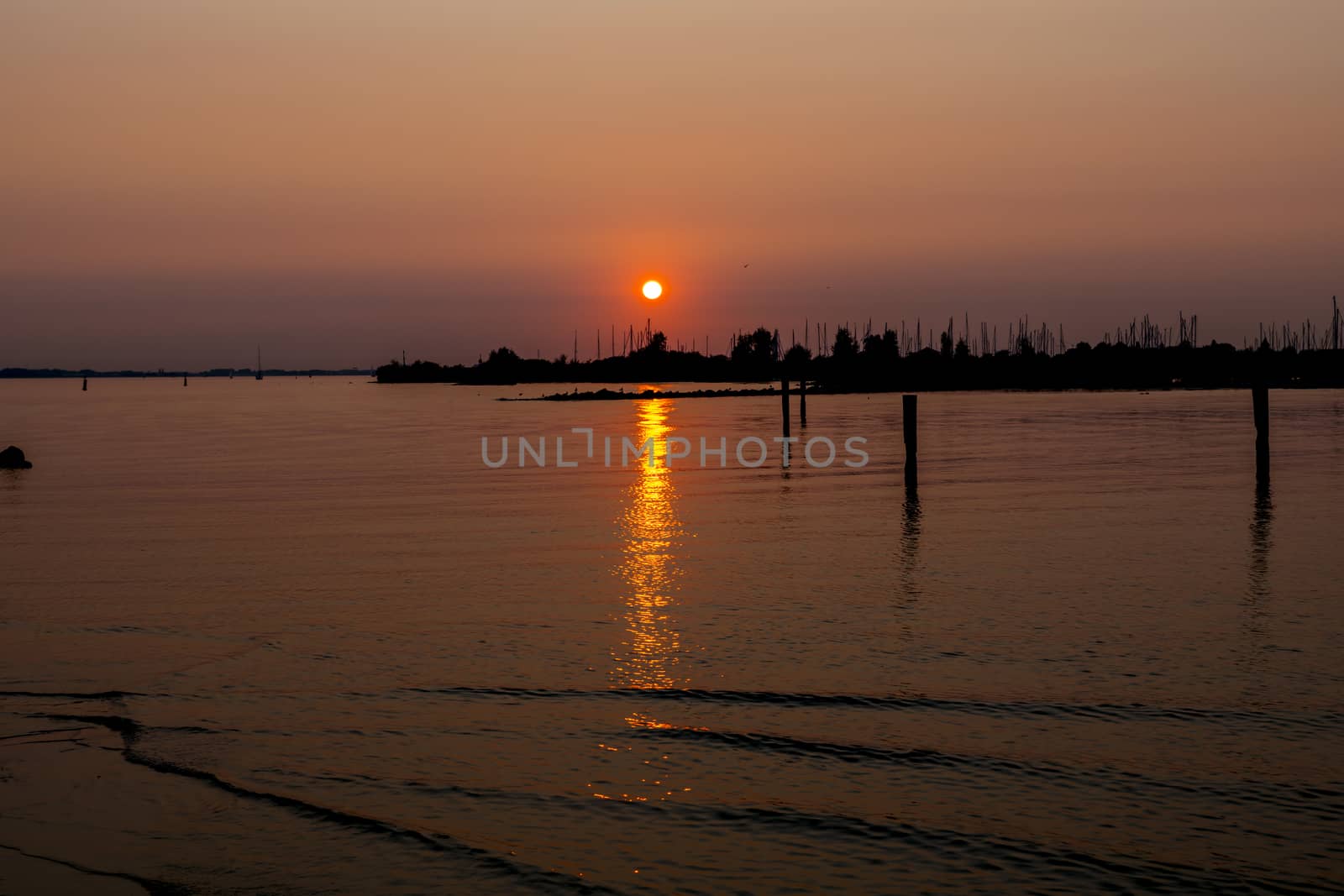sunset over the harbor of Hellevoetsluis with the boats with masts in silhouette as background and the sky orange red
