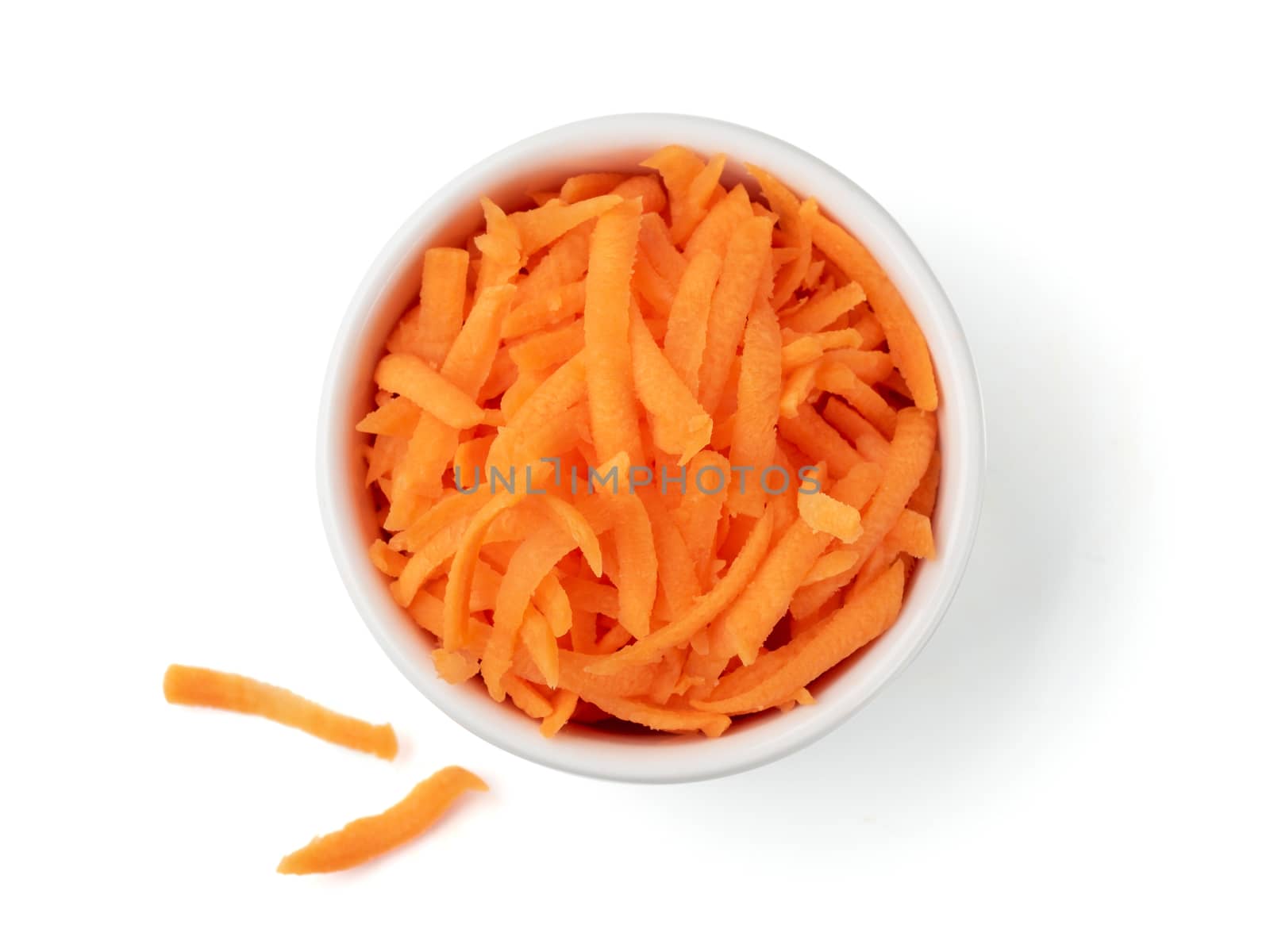 Fresh organic shredded carrots in small white bowl. Raw grated carrots isolated on white with clipping path. Top view or flat lay.