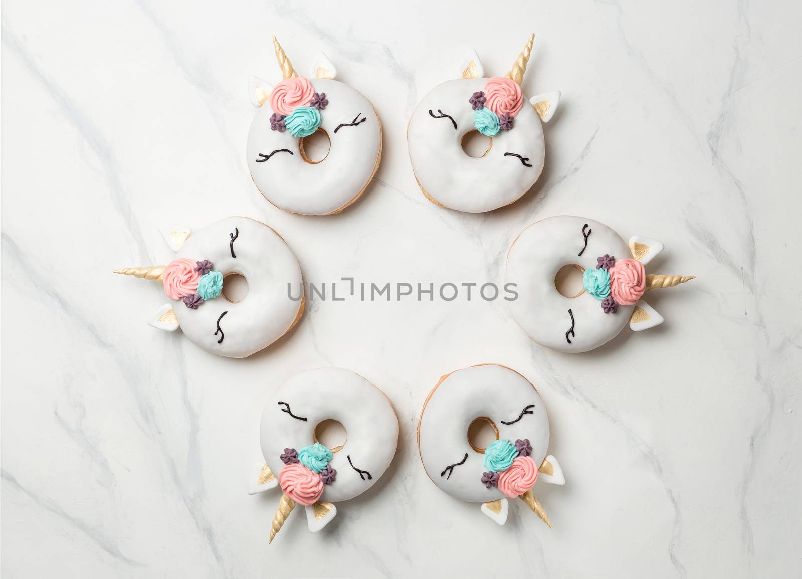 Unicorn donuts over white marble background. Trendy donut unicorn with white glaze in circle shape. Top view or flat lay. Copy space for text.
