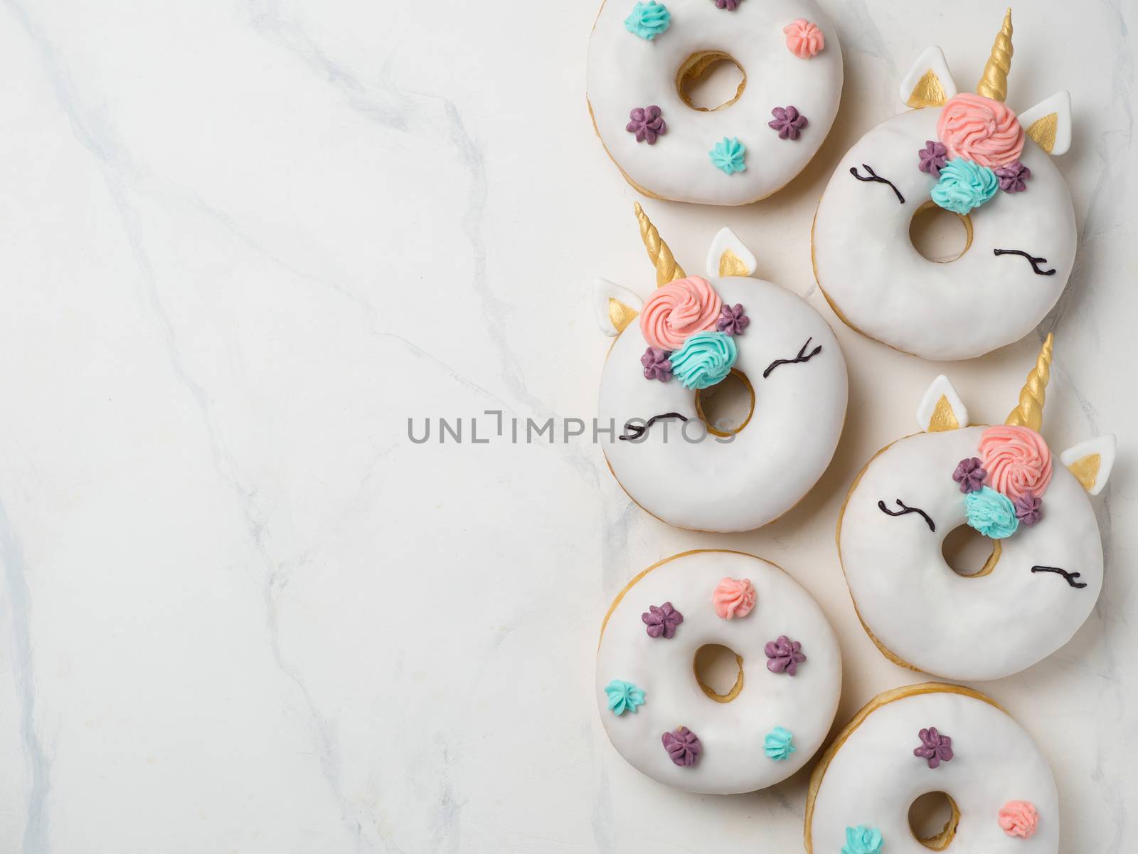 Unicorn donuts over white marble background. Trendy donut unicorn with white glaze. Top view or flat lay. Copy space for text.