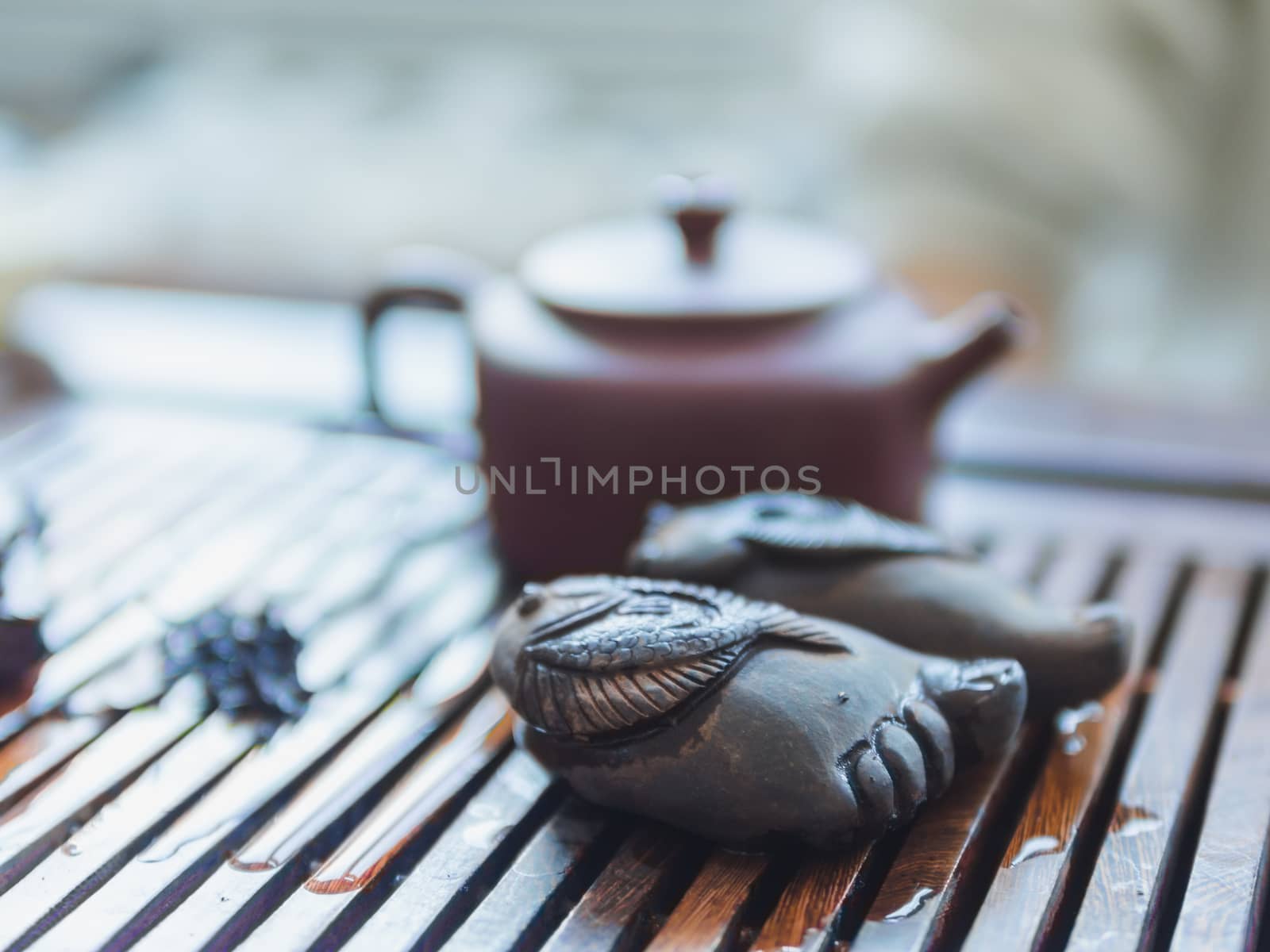 Chinese tea ceremony. Close up view of buddha foot figure and clay teapot on wooden tabletop. Pu erh tea ceremony.