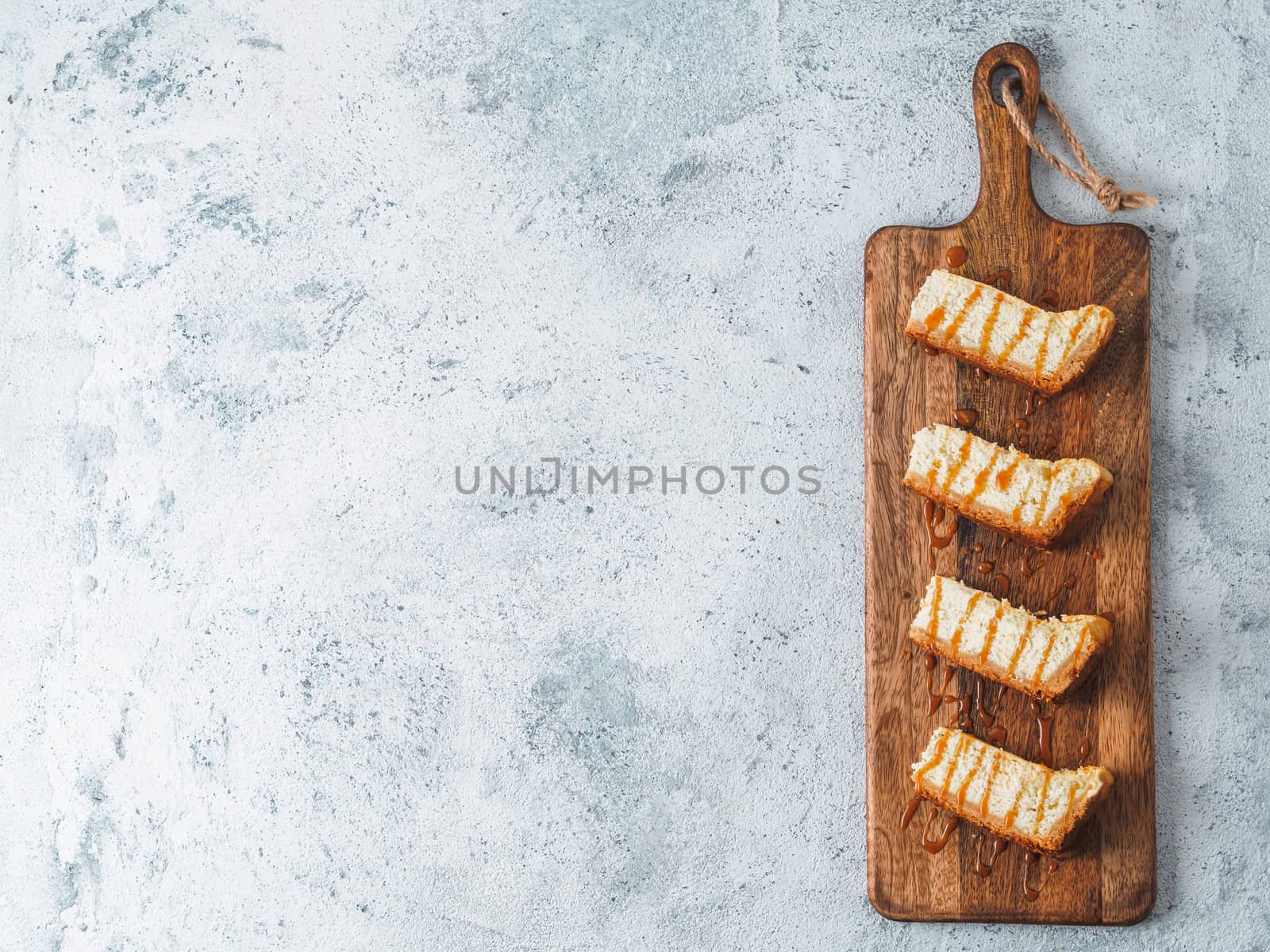 caramelized cheesecake slices on wooden cuttingboard. Cheesecake on gray cement background with copy space for text. Top view or flat lay.