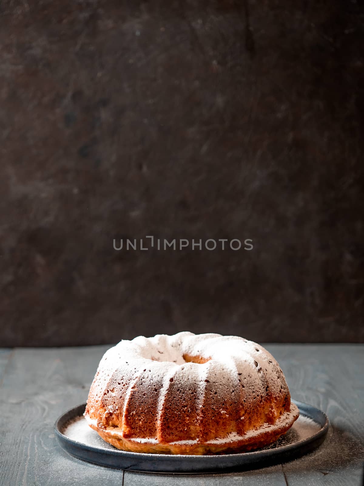 Female hand sprinkling icing sugar on muffin cake by fascinadora