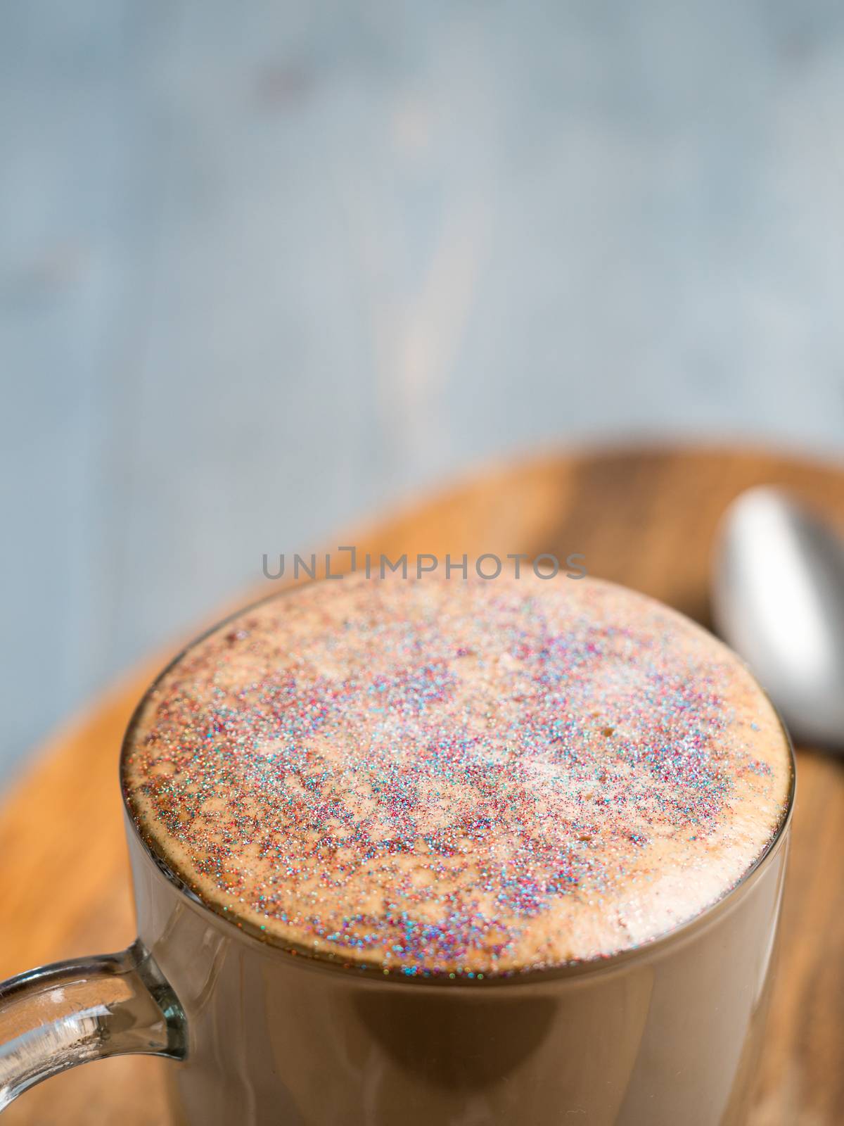 Trendy Coffee with edible glitter. Cup of sparkly coffee or diamond cappuccino on gray table. Copy space for text