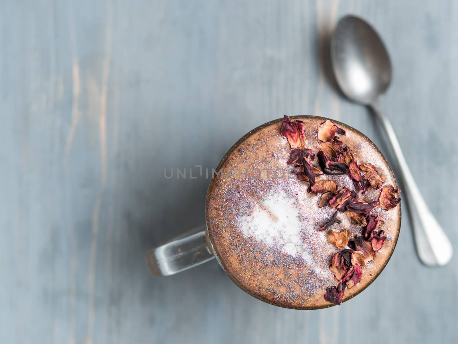 Trendy Coffee with edible glitter and dried rose petals. Cup of sparkly coffee or diamond cappuccino on gray table. Copy space for text