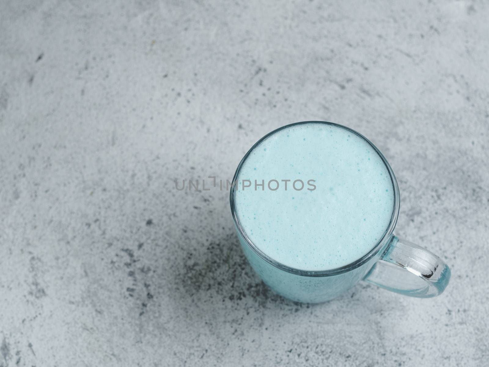 Trendy drink: Blue latte. Top view of hot butterfly pea latte or blue spirulina latte on gray cement textured background. Copy space for text. Top view or flat lay.