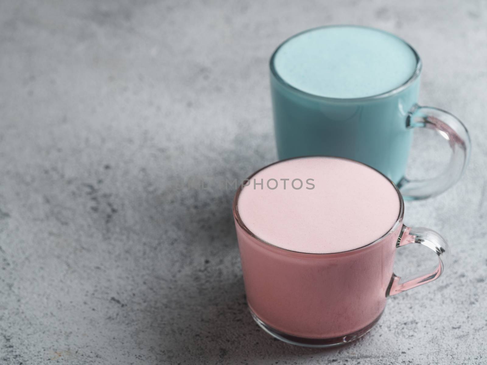 Trendy drink: Blue and pink latte. Top view of hot butterfly pea latte or blue spirulina latte and pink or raspberry beetroot latte on gray cement textured background. Copy space for text.