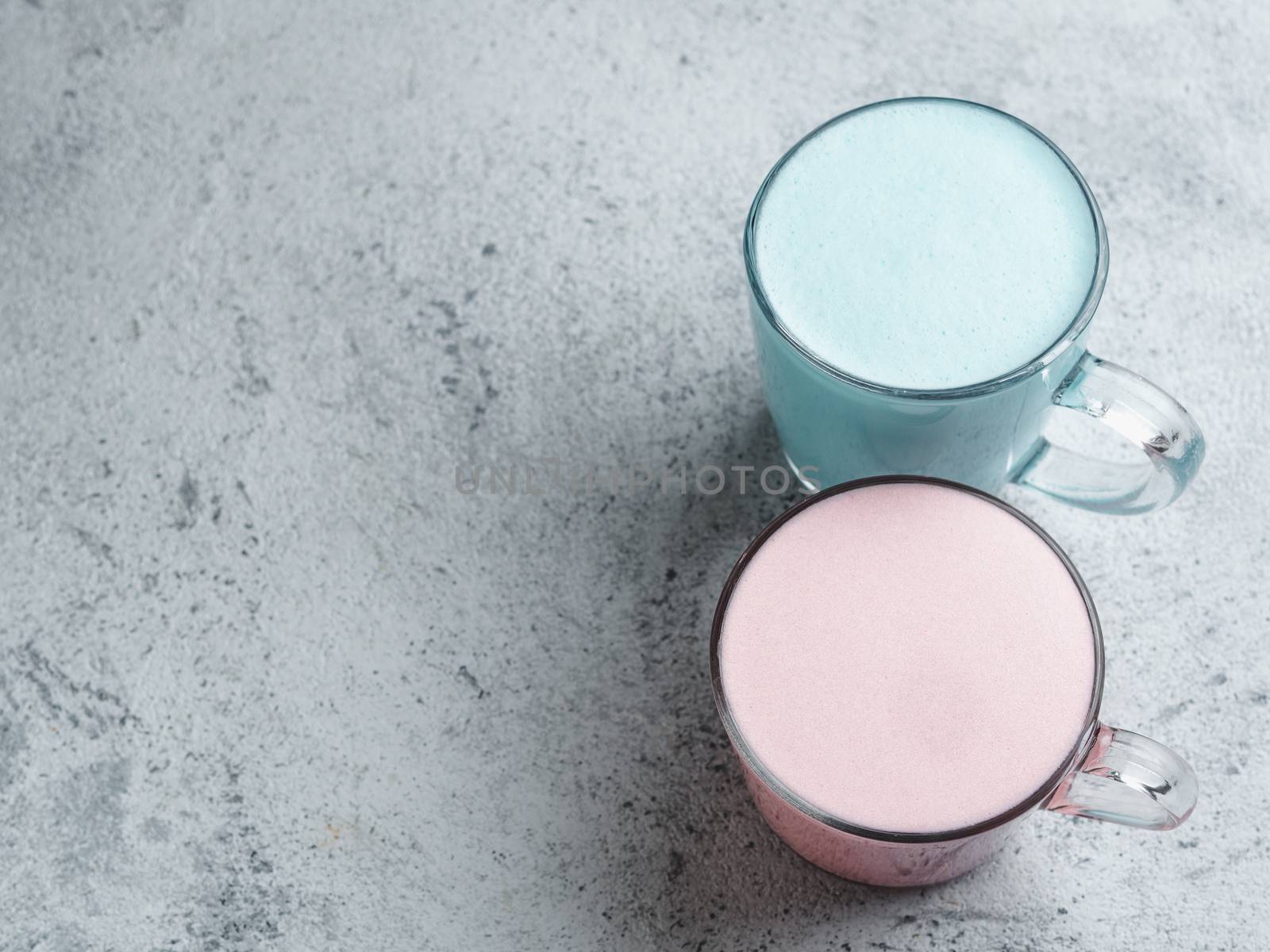Trendy drink: Blue and pink latte. Top view of hot butterfly pea latte or blue spirulina latte and pink beetroot or raspberry latte on gray cement textured background. Copy space. Top view or flat lay