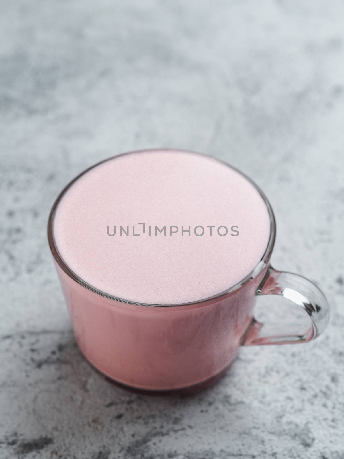 Trendy drink: pink latte. Beetroot or raspberry latte on gray cement background. Vertical. Copy space for text