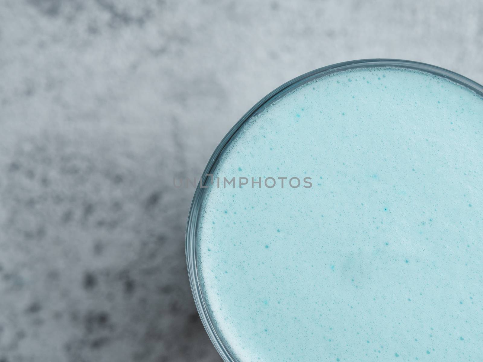 Trendy drink: Blue latte. Close up view of hot butterfly pea latte or blue spirulina latte on gray cement textured background. Copy space for text. Top view or flat lay.