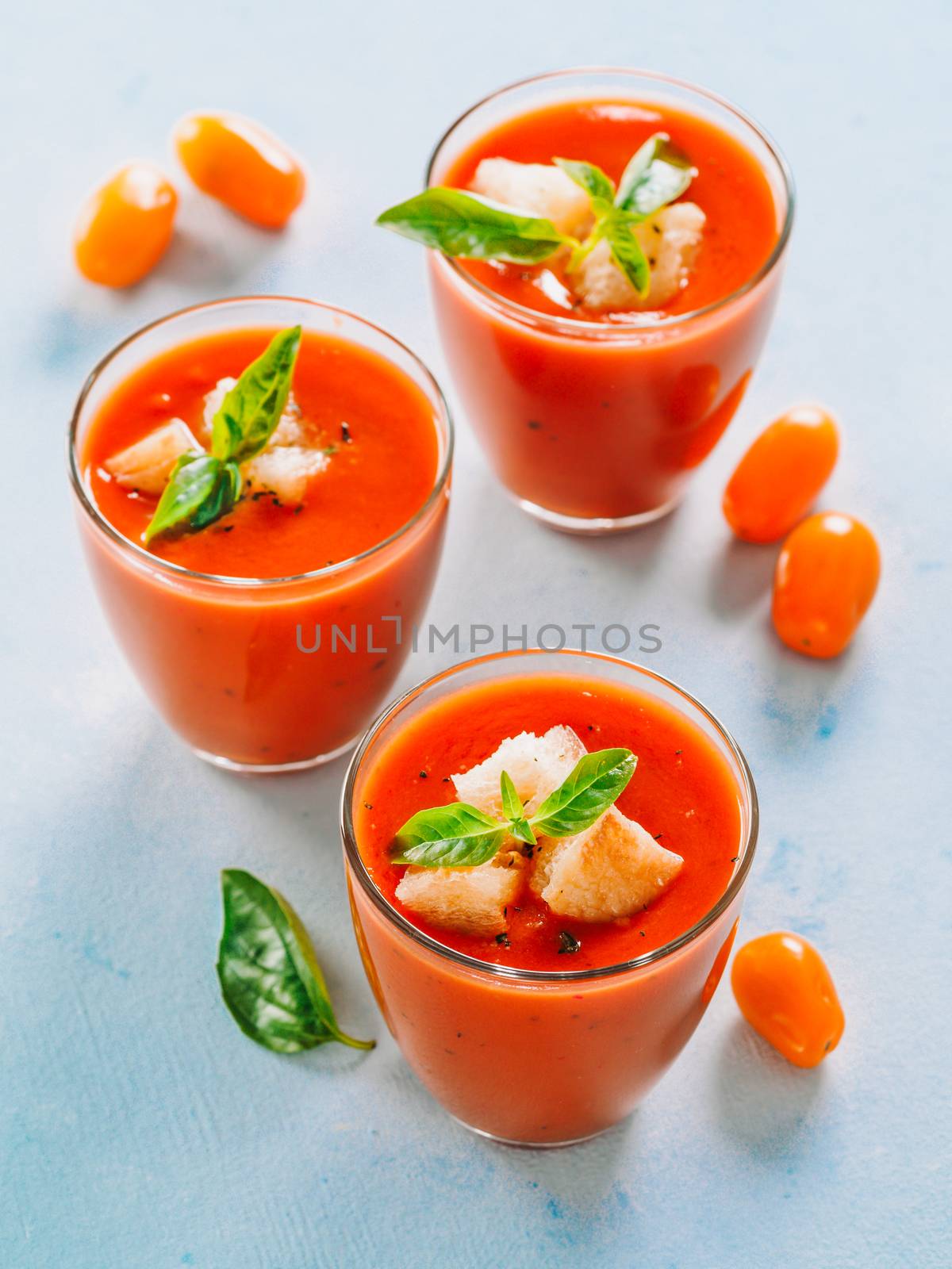 Delicious gaspacho soup in glass. Traditional spanish cold soup puree gaspacho or gazpacho on gray cement background. View from above or top view or flat lay. Vertical.
