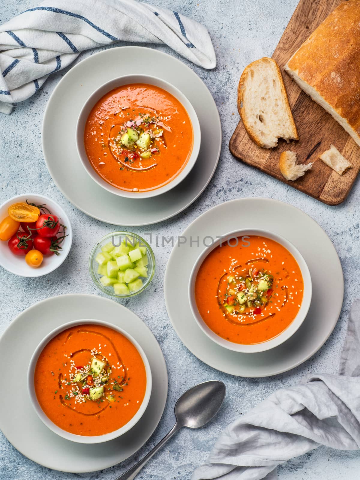 Gaspacho soup on white marble tabletop. Three bowls of traditional spanish cold soup puree gaspacho or gazpacho on light gray or white marble background. Top view or flat lay. Vertical