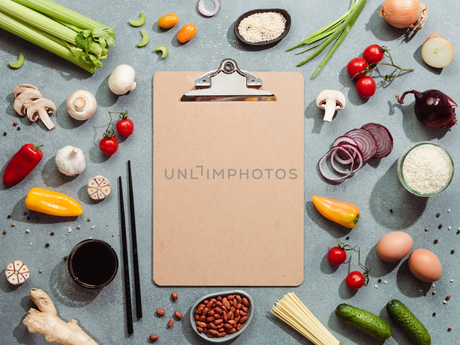 Asian ingredients and empty clipboard. Various of Chinese cooking ingredients and chopsticks on gray stone background. Asian food recipes concept. Copy space for text. Top view or flat lay.