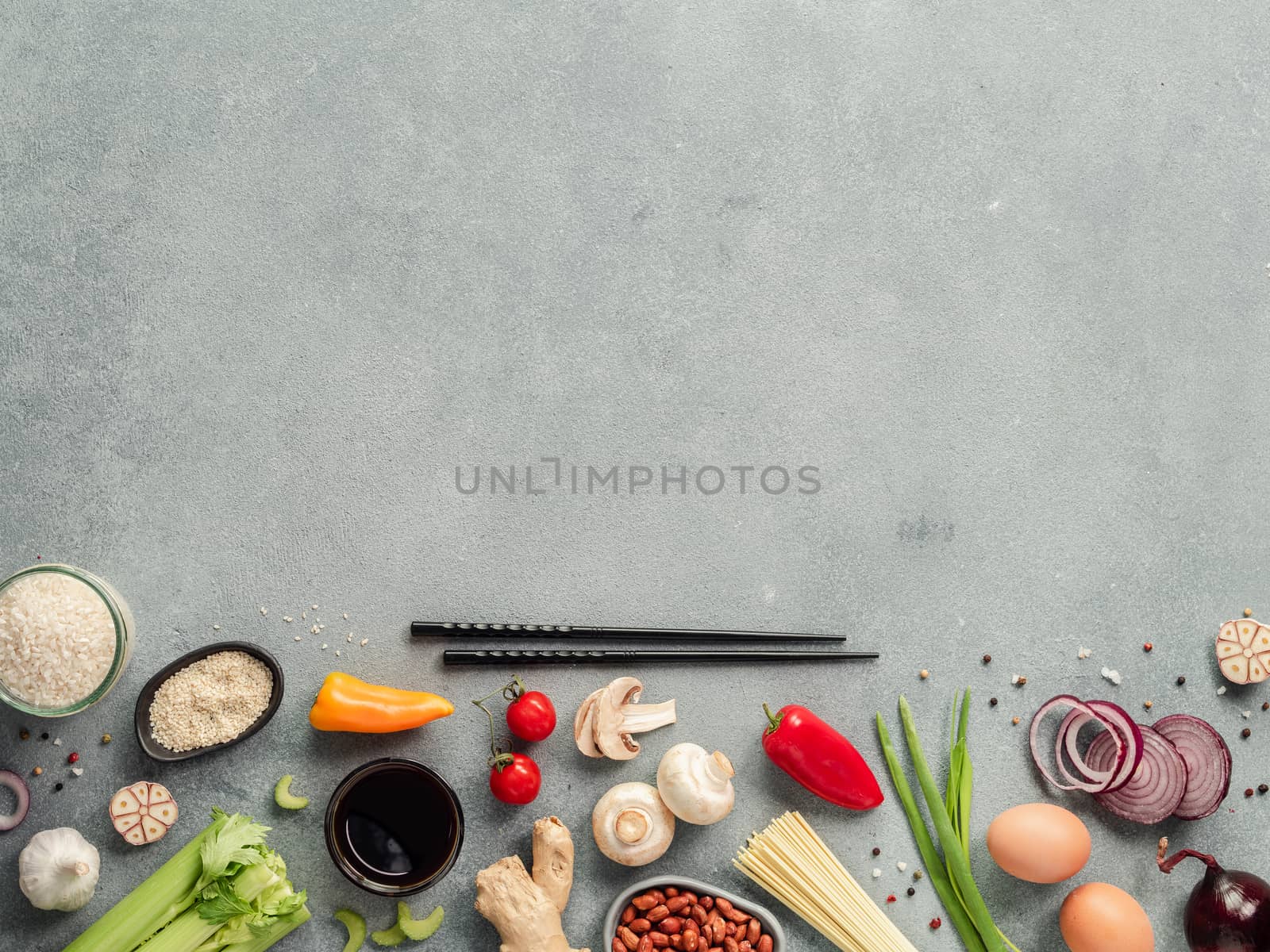 Asian food ingredients with copy space. Various of Chinese cooking ingredients and chopsticks on gray stone background. Asian food concept. Copy space for text. Top view or flat lay. Hard light