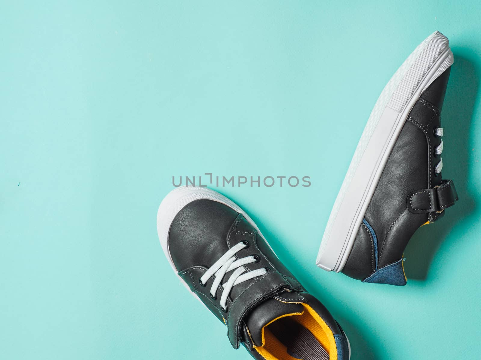 pair of new kids or adult sneakers on blue background, top view. Flat lay gray and yellow or mustard color sneakers shoes on colorful bright blue background with copy space for text or design