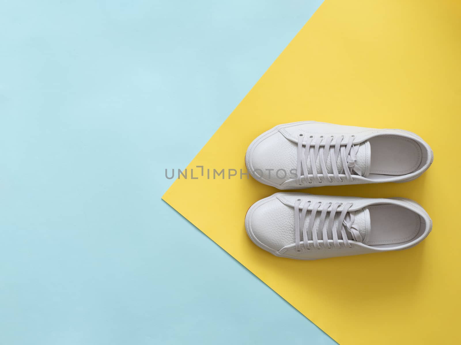 White sneakers on blue and yellow, copy space, top view by fascinadora