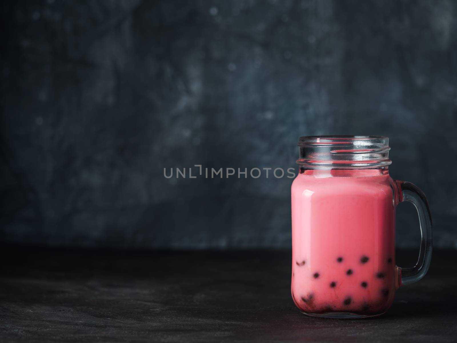 Homemade Milk Bubble Tea with Tapioca Pearls balls. Popular Taiwan bubble tea in glass mason jar with copy space for text. Bubble tea on dark background.