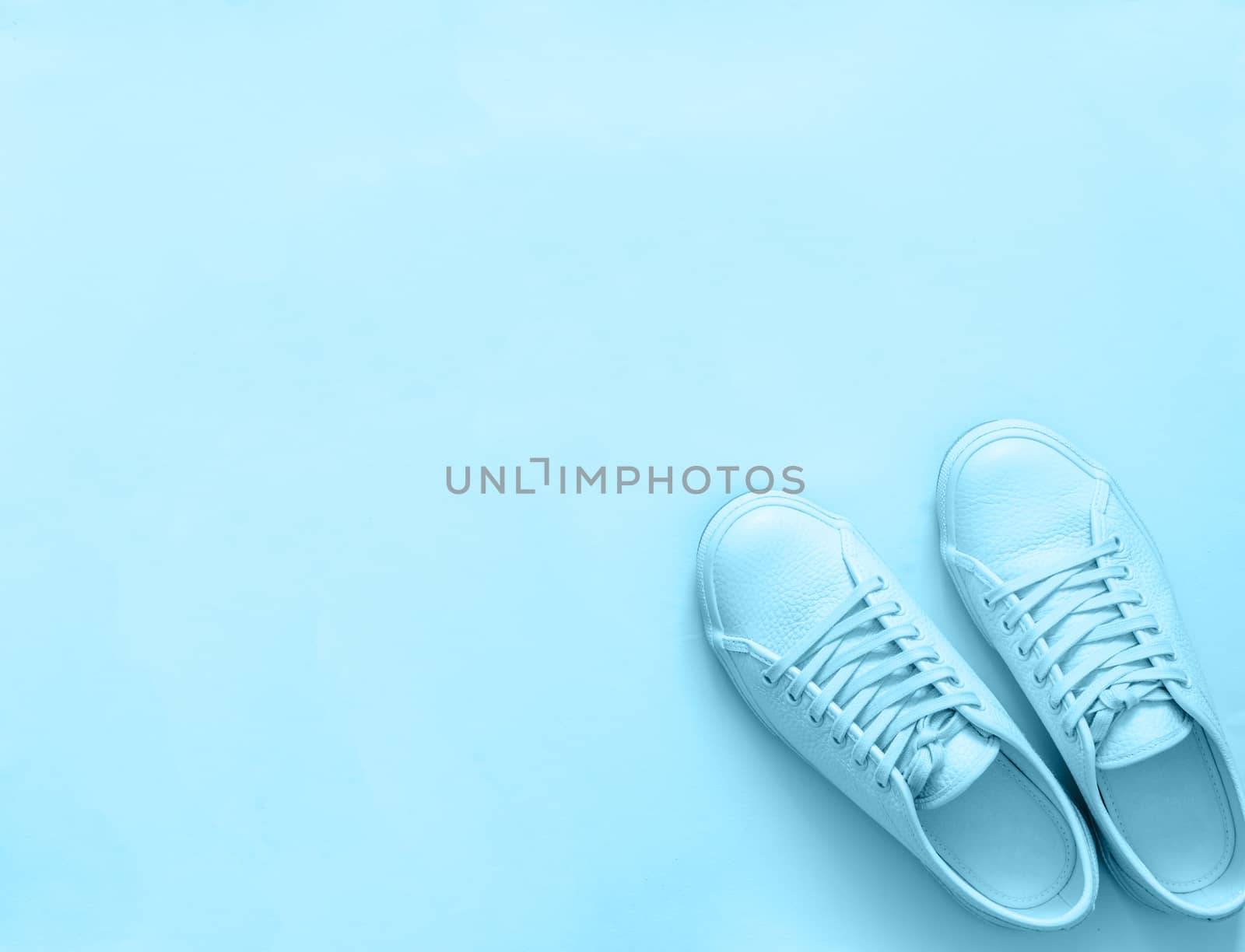 Blue leather sneakers on blue background. Pair of blue sport shoes or sneakers with copy space for text or design. Overhead shot of new blue sneakers, monochrome. Top view or flat lay