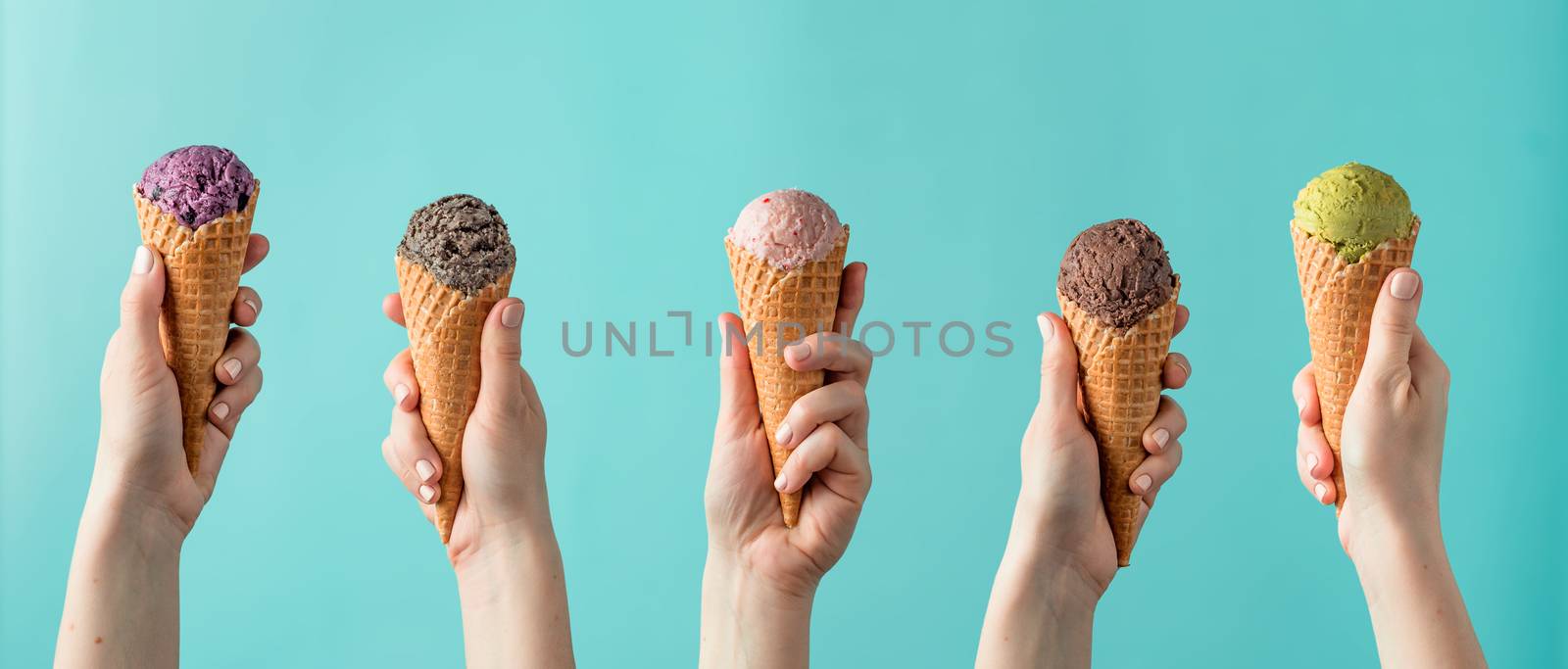 Hands holding ice cream in cones on blue background. Ice cream scoop in cones assortment in woman hands on blue background. Banner