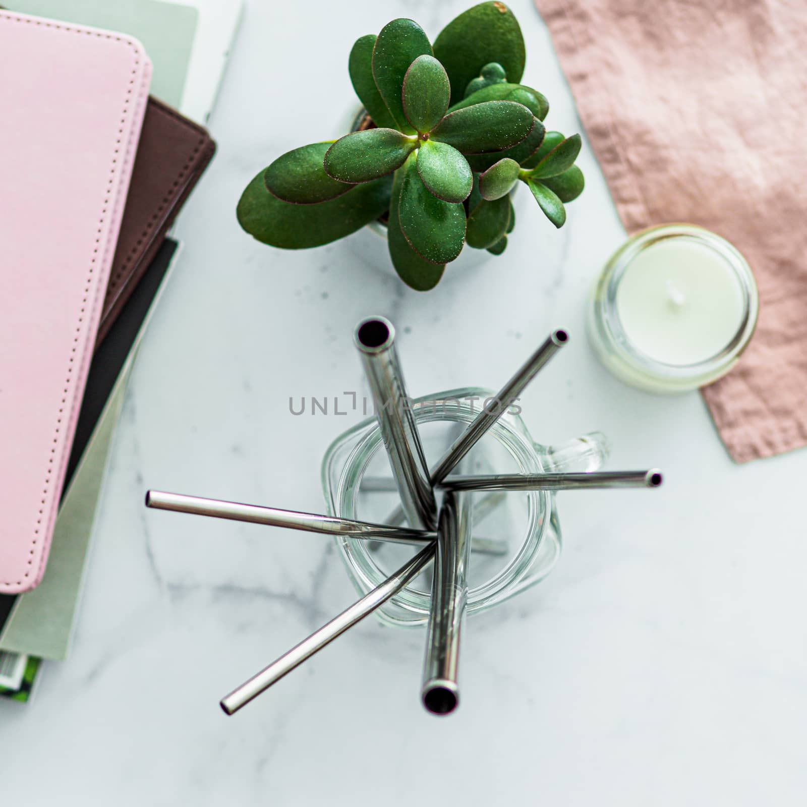 Metal drinking straws in glass mason jar on white marble table indoor. Metal straws on table in living room interior. Recyclable straws, zero waste concept. Top view or flat lay