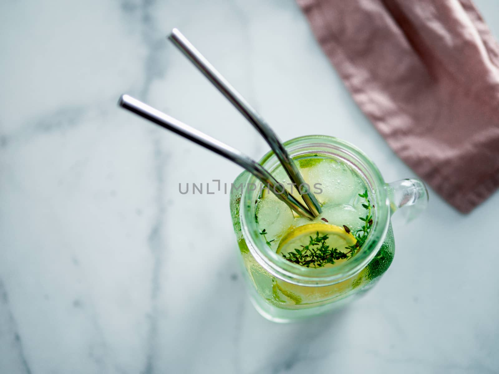 Metal drinking straws and cold drink in glass mason jar on white marble background. Top view or flat lay. Copy space for text or design. Recyclable straws, zero waste concept. Banner.