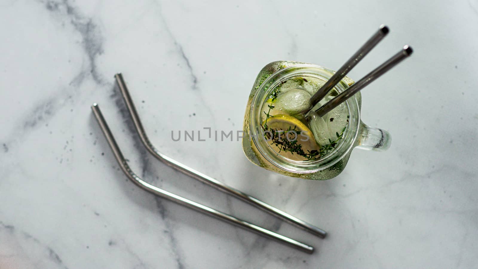 Metal drinking straws and cold drink in glass mason jar on white marble background. Top view or flat lay. Copy space for text or design. Recyclable straws, zero waste concept. Banner.