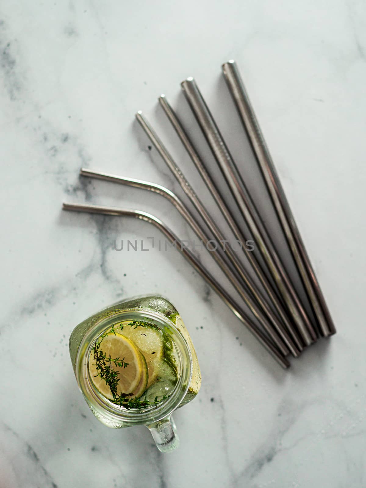 Metal drinking straws and cold drink in glass mason jar on white marble background. Top view or flat lay. Recyclable straws, zero waste concept. Banner. Vertical