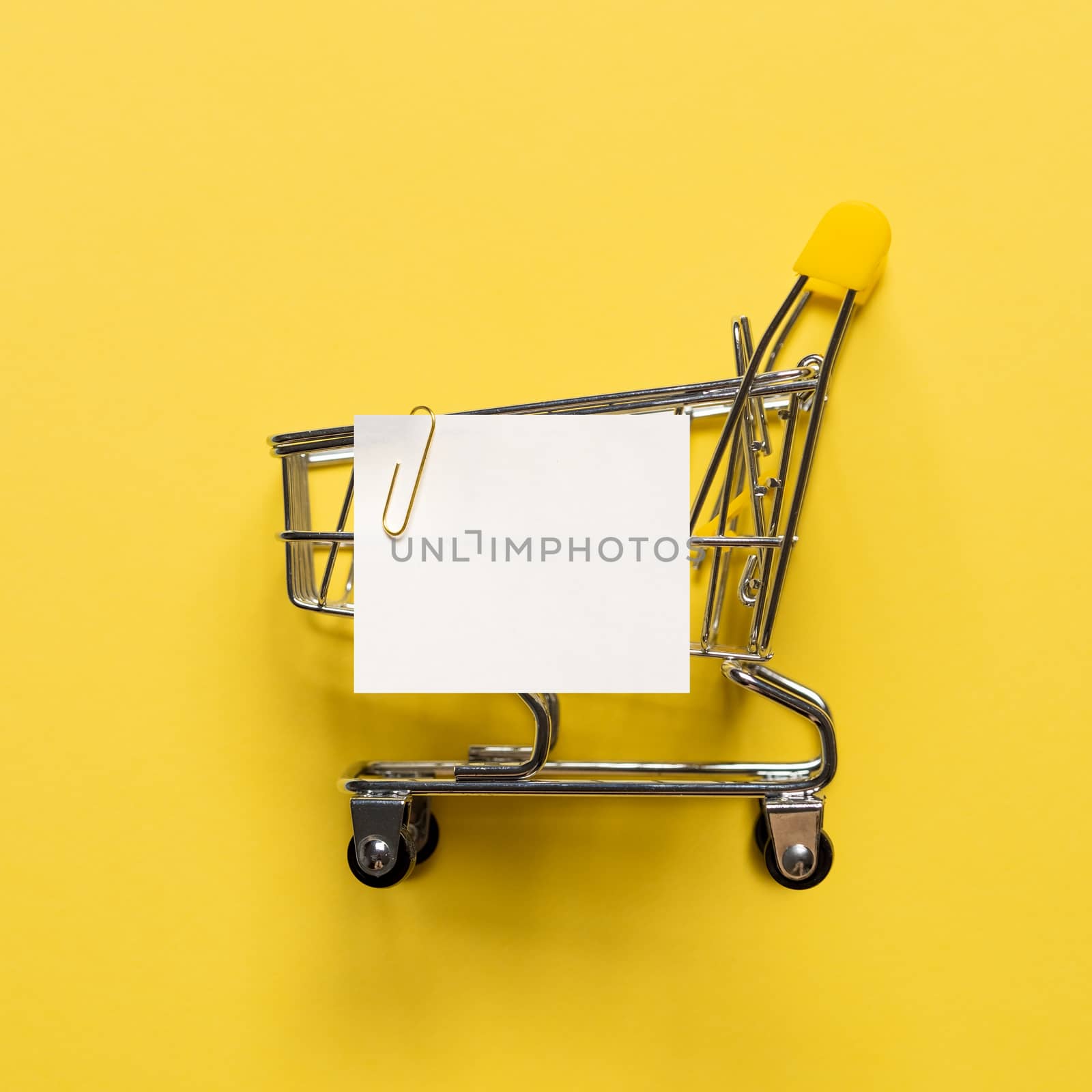 Shopping cart and white paper note list on yellow by fascinadora