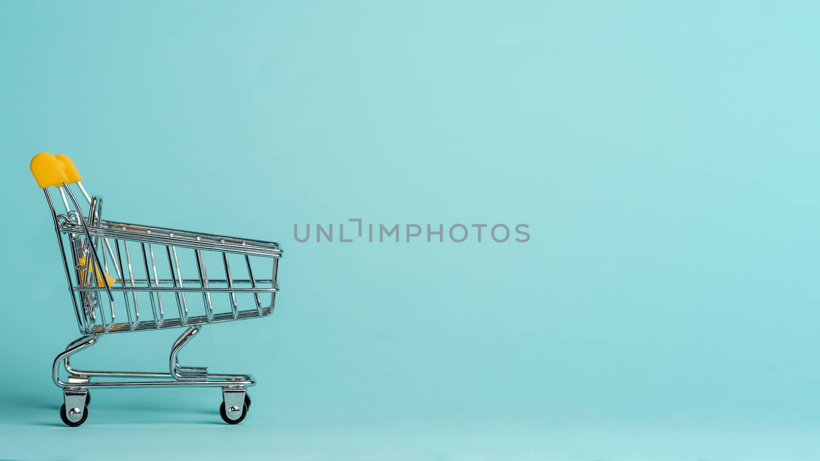 Shopping cart on blue background. Shop trolley at supermarket as sale, discount, shopaholism concept with copy space for text or design.