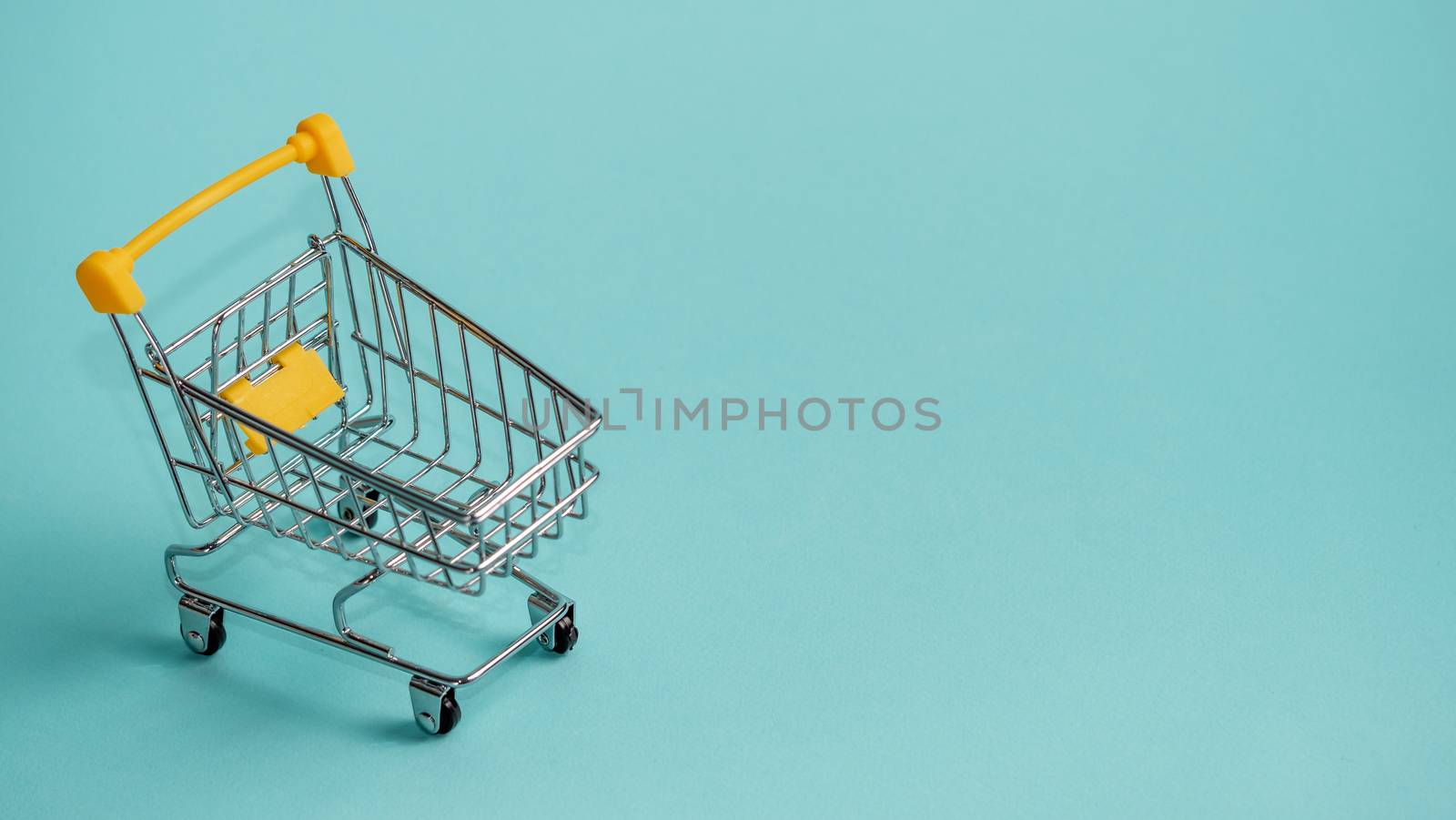 Shopping cart on blue background. Shop trolley at supermarket as sale, discount, shopaholism concept with copy space for text or design.