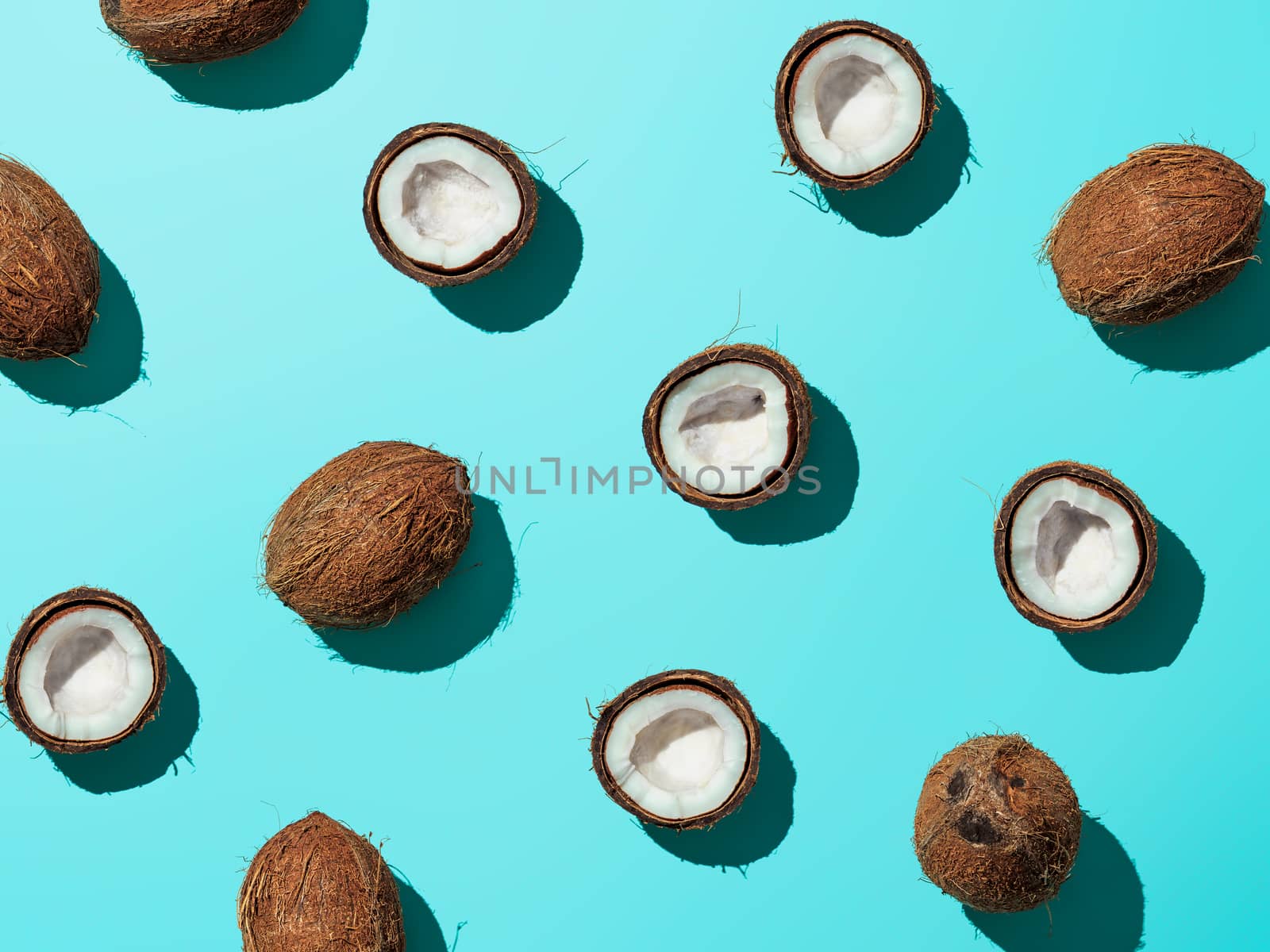 Creative layout of coconuts half on blue background. Tropical pattern, top view or flat lay. Hard light pop art minimal summer background. Horizontal