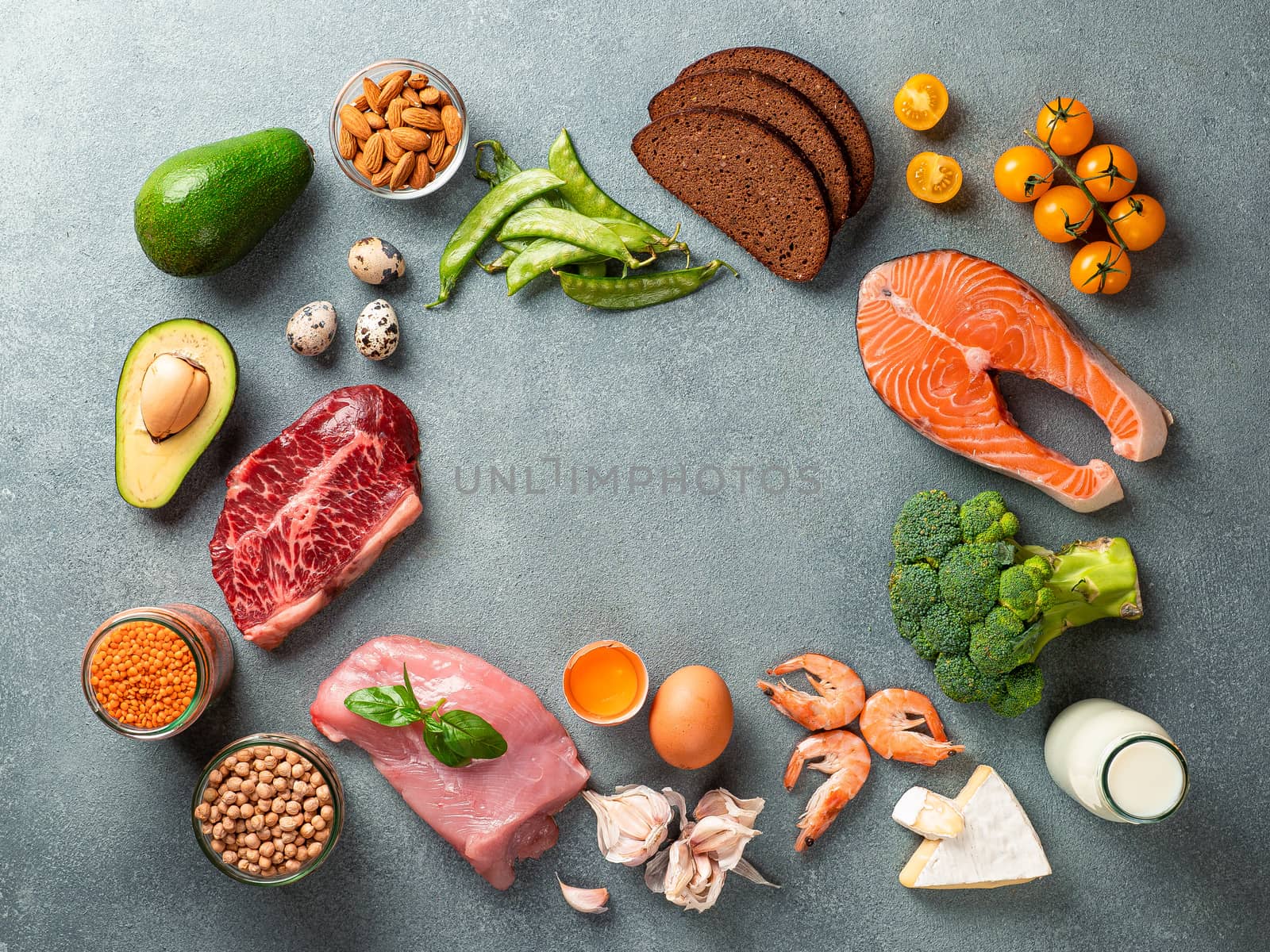 Balanced diet with copy space in center. Various healthy food ingredients on gray stone background. Top view or flat lay.