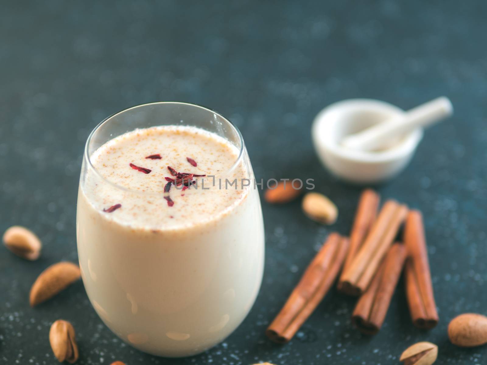 Thandai or Sardai cold drink made during Holi festival. Cold milk drink in glass, with ingredients - nuts and spices. Copy space