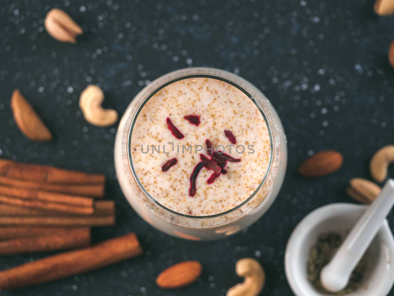 Thandai or Sardai cold drink made during Holi festival. Cold milk drink in glass, with ingredients - nuts and spices. Copy space
