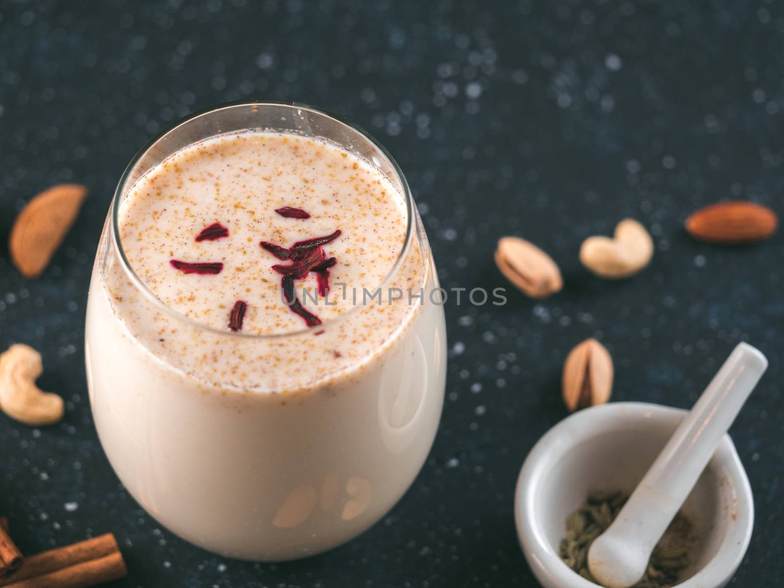 Thandai or Sardai cold drink made during Holi festival. Cold milk drink in glass, with ingredients - nuts and spices. Copy space