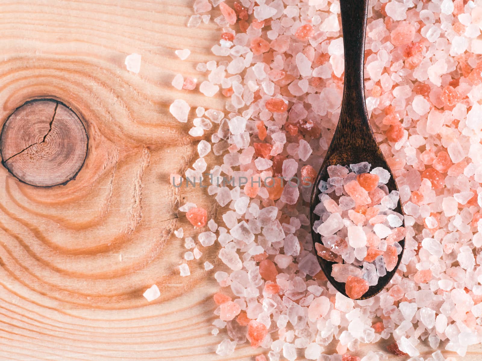 Himalayan pink salt in spoon on wooden background. Copy space