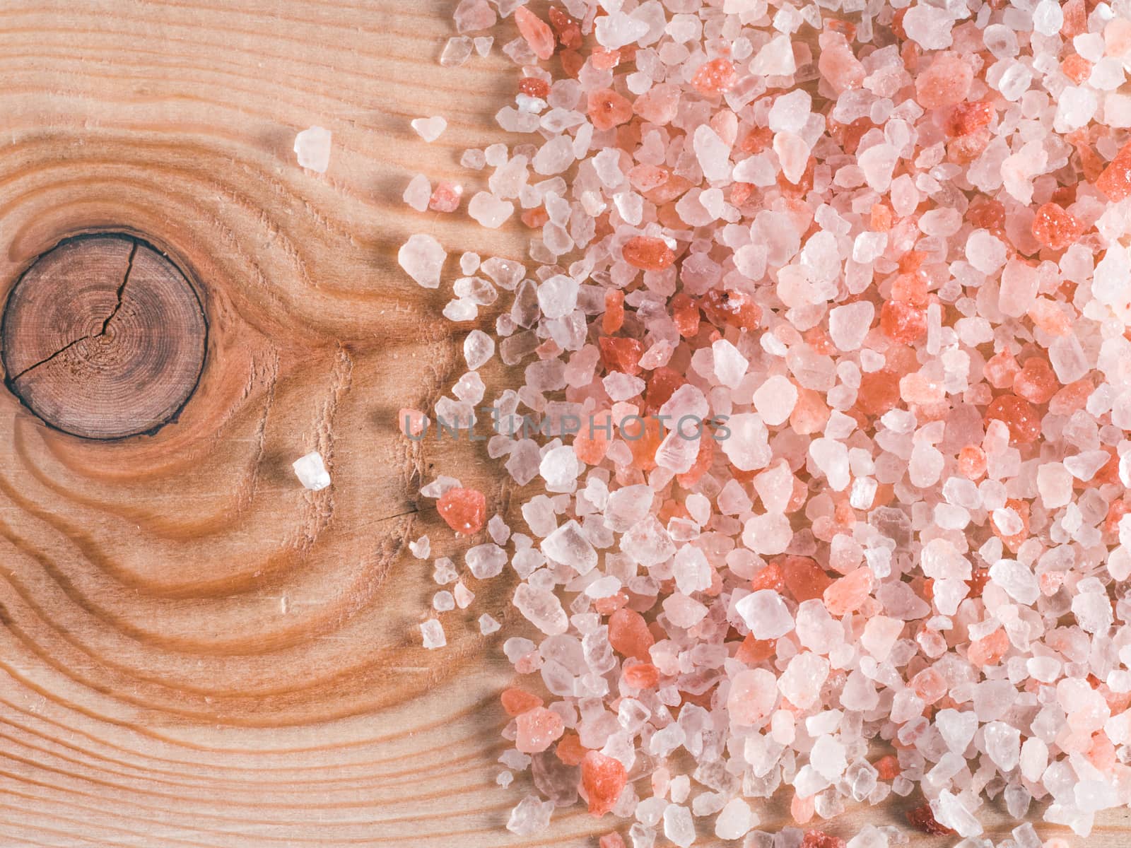 Himalayan pink salt in crystals on wooden background. Copy space