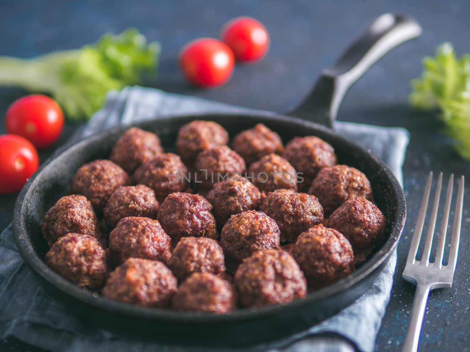 Homemade roasted beef meatballs in cast-iron skillet on dark blue background. Copy space for text. Shallow DOF