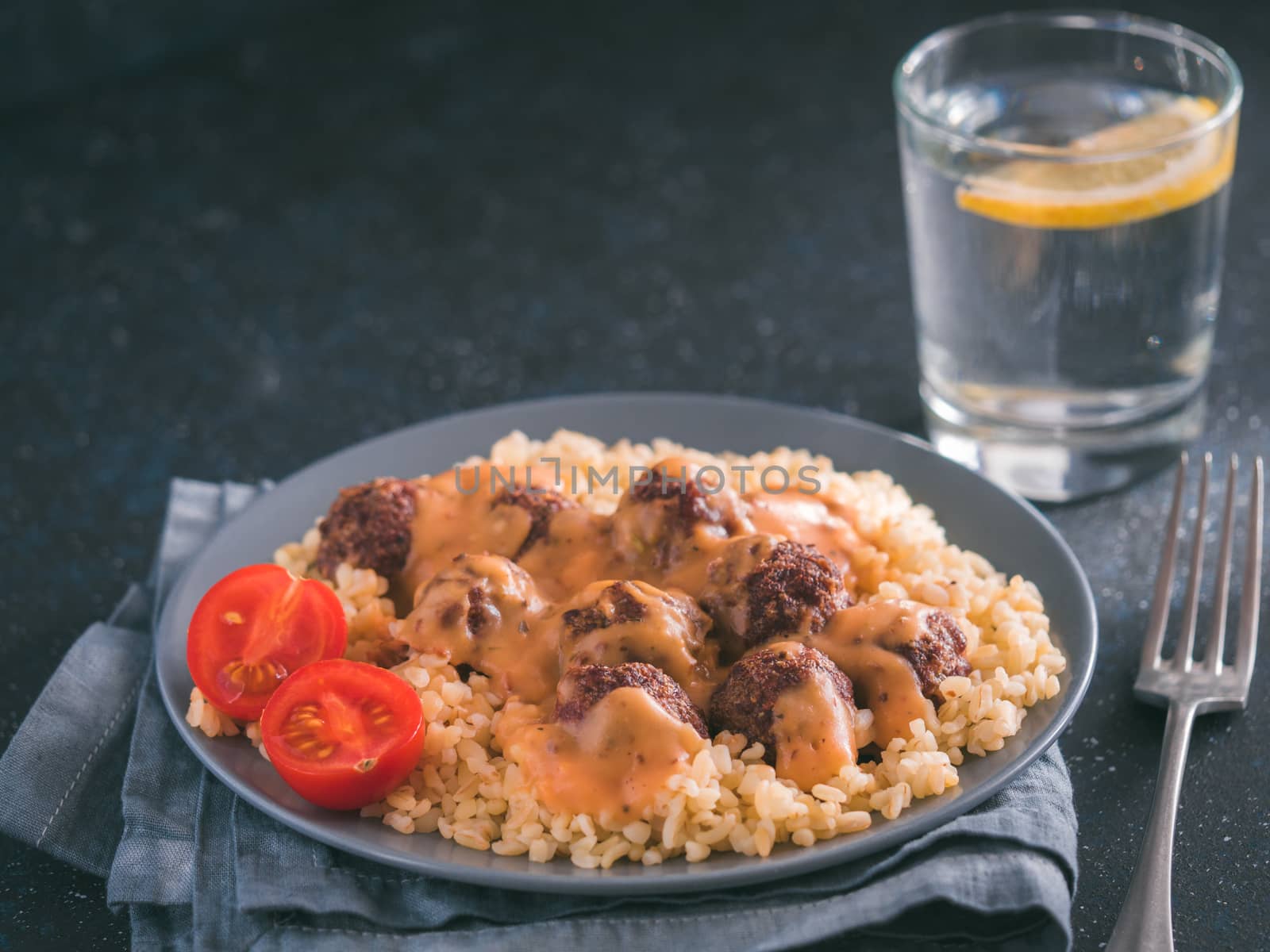 Bulgur dish idea and recipe. Bulgur with homemade roasted beef meatballs on dark blue background. Copy space for text