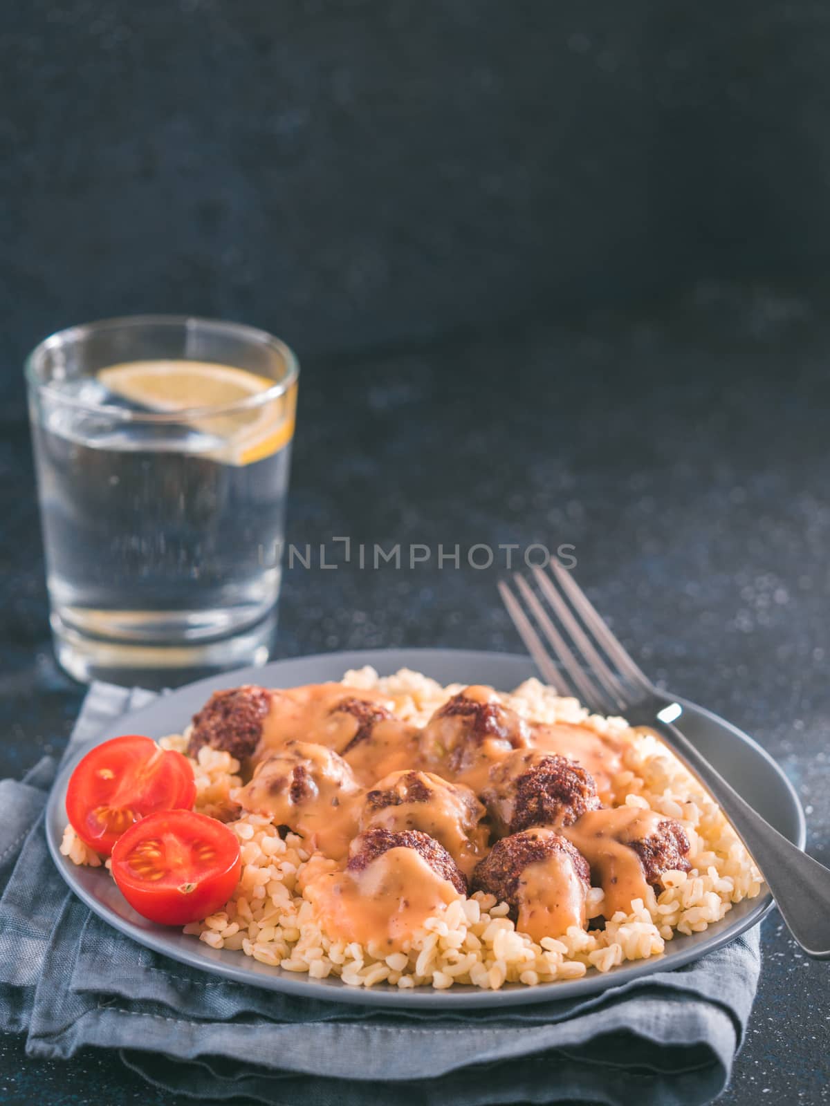 Bulgur dish idea and recipe. Bulgur with homemade roasted beef meatballs on dark blue background. Copy space for text