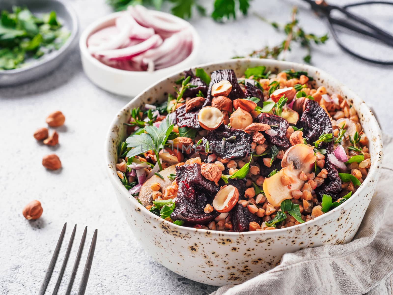 Warm buckwheat and beetroot salad on gray background. Vegetarian diet idea and recipe -salad with beetroot, buckwheat, mushrooms, onion, fresh herbs,hazelnut