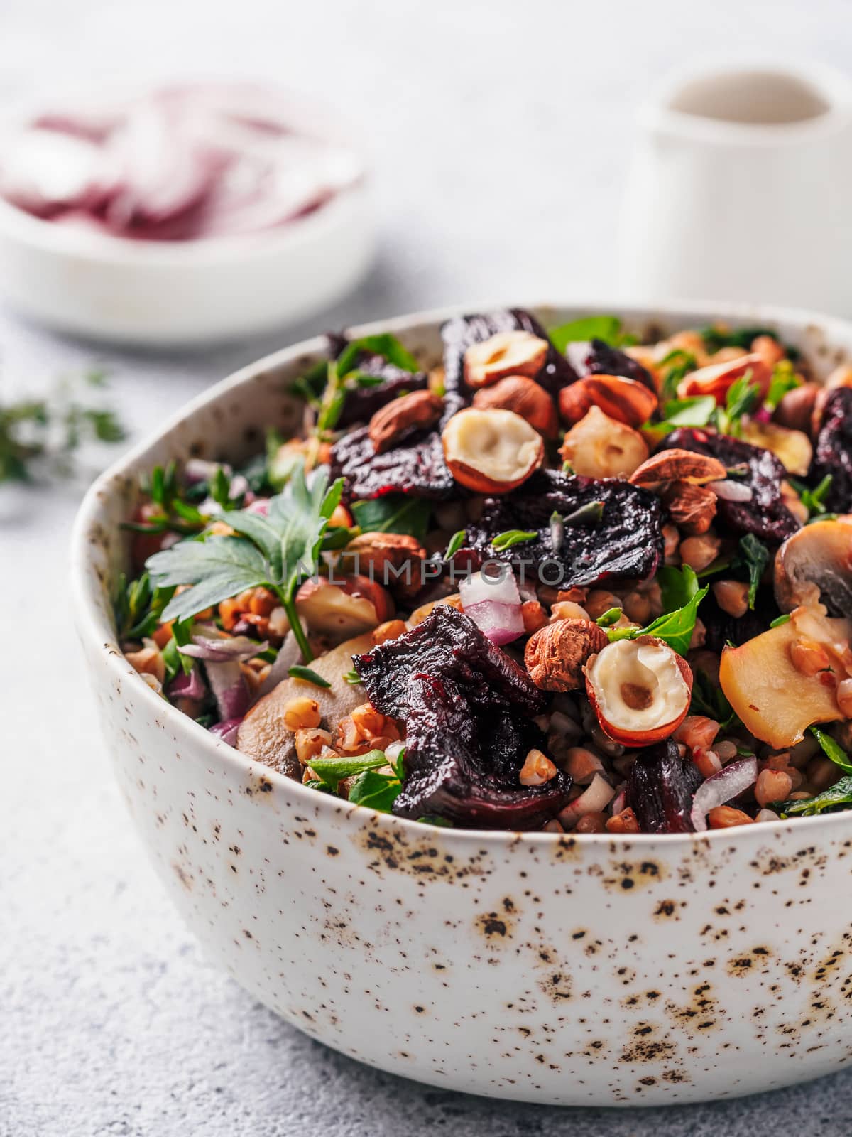 Warm buckwheat and beetroot salad on gray background. Vegetarian diet idea and recipe -salad with beetroot, buckwheat, mushrooms, onion, fresh herbs,hazelnut. Copy space for text