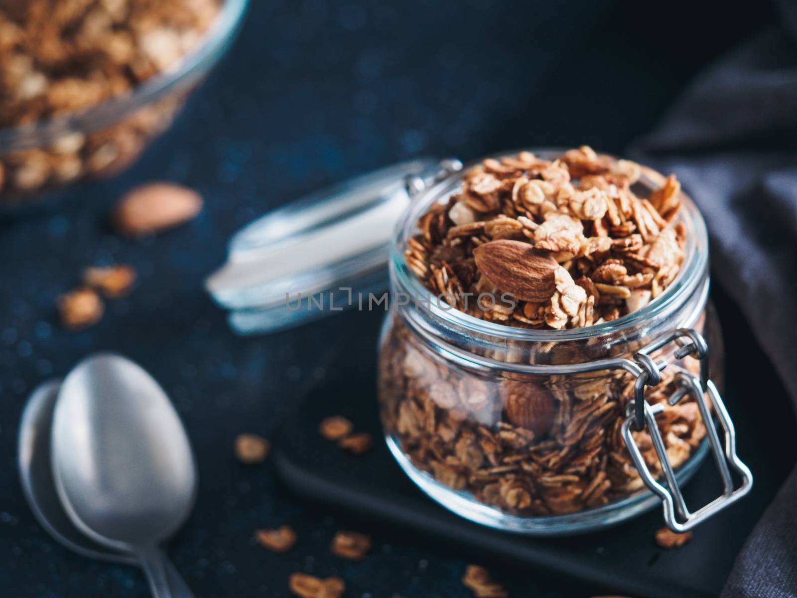 Homemade granola in glass jar on dark table. Ingredients for healthy breakfast. Copy space for text. Low key. Selective focus. Shallow DOF