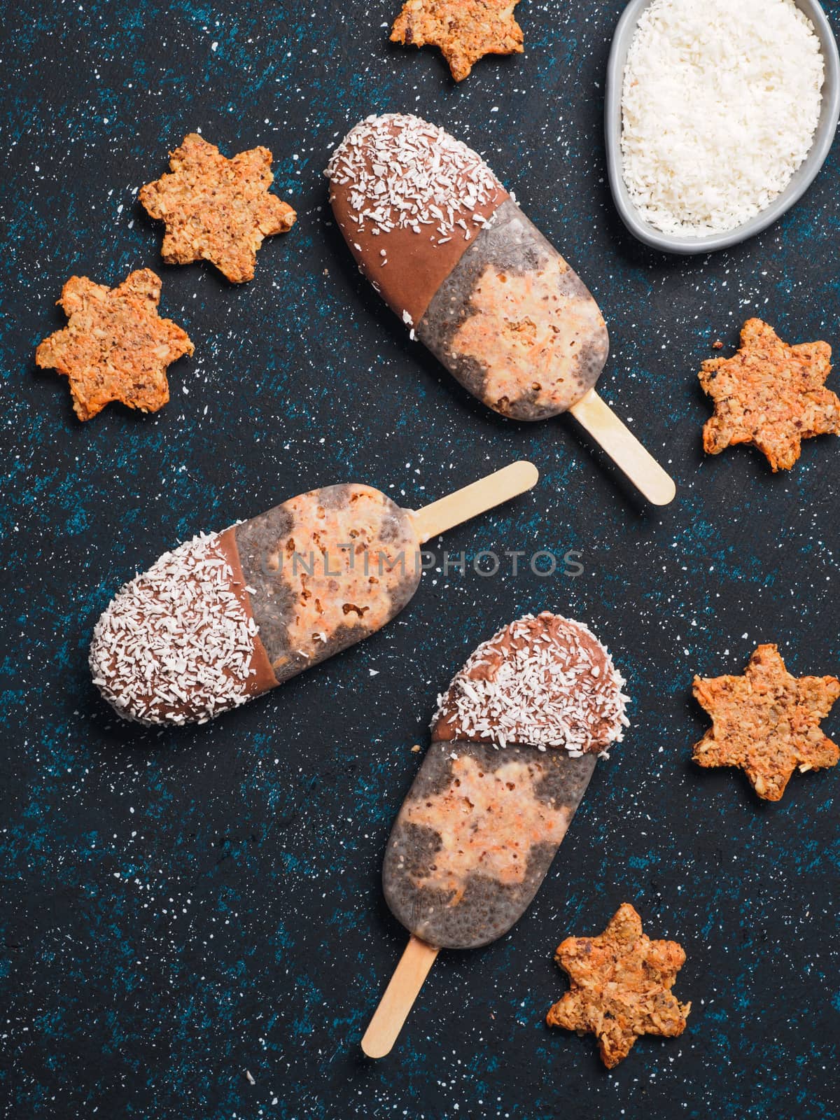 Chia popsicle with raw carrot cake and chocolate on dark blue background. Healthy recipe and idea homemade vegan popsicle ice cream. Easter dessert idea. Top view or flat-lay. Copy space for text.