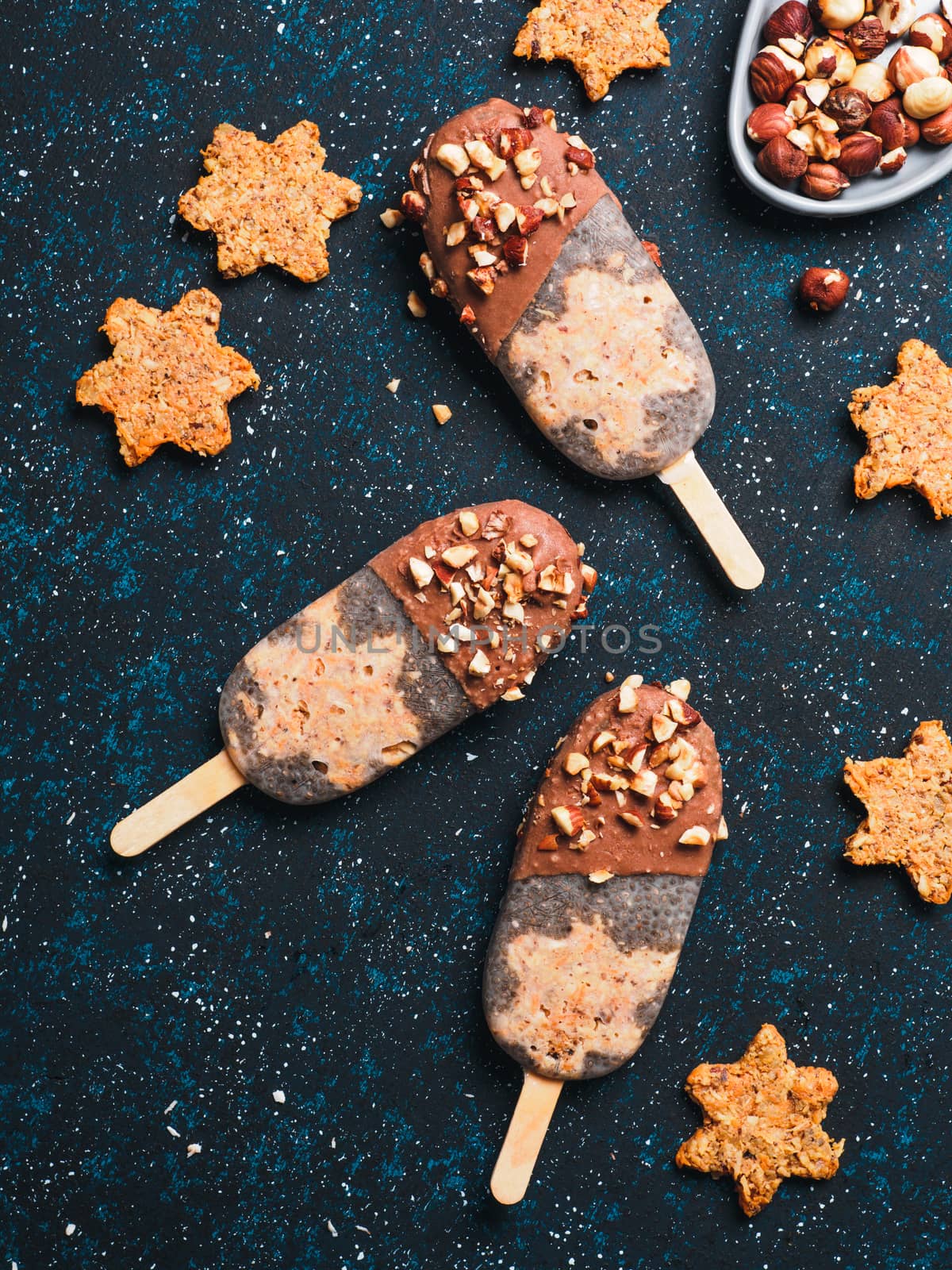 Chia popsicle with raw carrot cake and chocolate on dark blue background. Healthy recipe and idea homemade vegan popsicle ice cream. Easter dessert idea. Top view or flat-lay. Copy space for text.